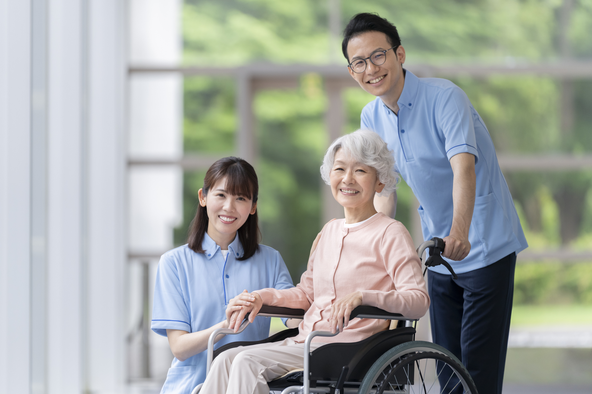 車いすの高齢女性とご家族、介護職員が笑顔で並ぶ様子