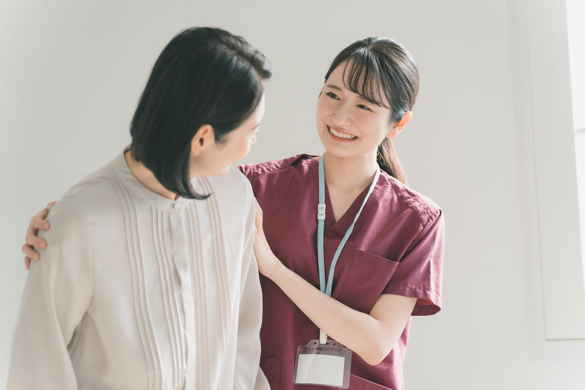 高齢女性の肩に手を添えて歩行を支える介護職員