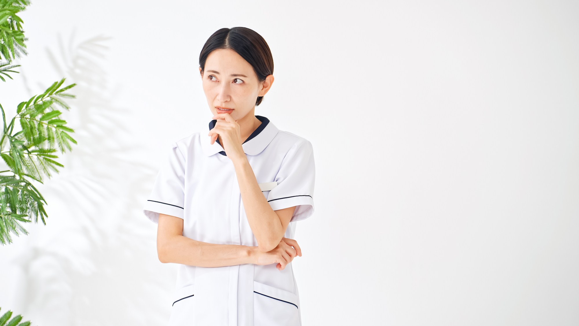 口元に手を当てて考え込む看護師