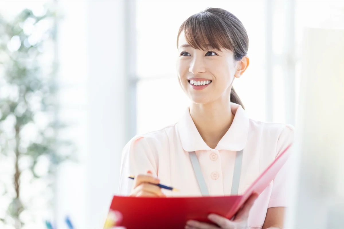 明るい室内で笑顔を見せるユニフォーム姿の女性介護職員