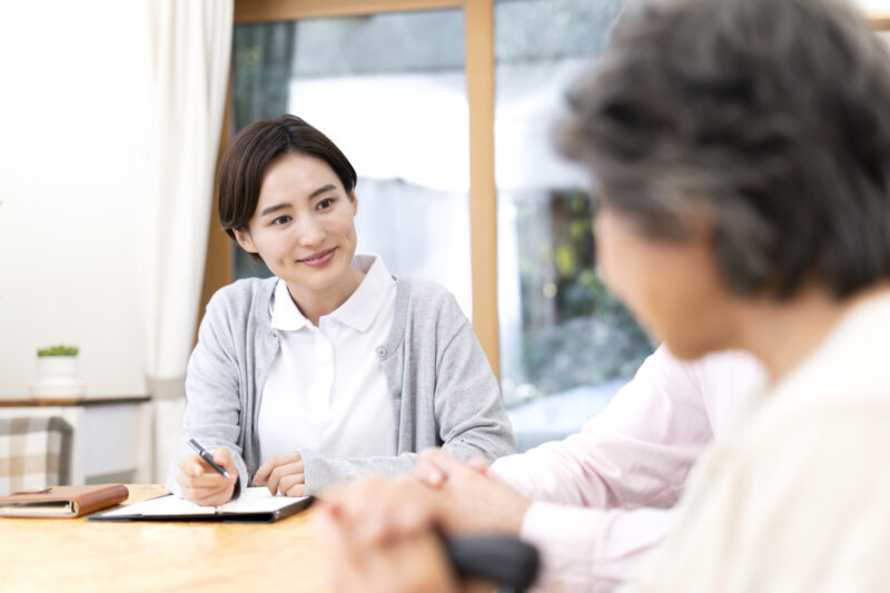 記録用紙に書き込みながら高齢女性の様子を確認する女性看護師